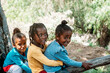© David Prado/Stocksy - Group of black children having fun over a tree trunk in forest