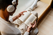 Young Man Reading A Book And Listening To Music 