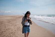 Young Woman Walking On The Beach With Photo Camera