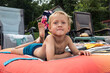 © Anna Tabakova/Stocksy - Little boy laying on a floaty on a deck