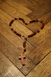 Czerwona koronka do Krwi Jezusa ułożona w kształcie serca na drewnianym tle