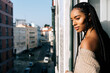 © David Prado/Stocksy - Beautiful black woman with braided long hair standing in a balcony