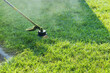 Closeup man hand using lawn trimmer mower cutting grass on green selective focus at hand