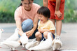 © Bo Bo/Stocksy - asian family feeding pigeon in the park