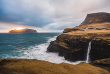 Cliff With Waterfall Near Sea During Sunset