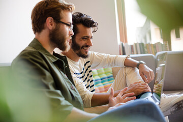 Casual businessmen working at laptop on sofa in office