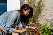 © Alba Vitta/Stocksy - Woman picking up strawberries in urban veggie garden