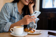 © Alba Vitta/Stocksy - Closeup of smiley woman holding phone in cafeteria