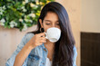 © Alba Vitta/Stocksy - Portrait of young woman drinking coffe in cafeteria