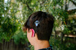 © Erin Brant/Stocksy - Back view of teen boy with Cochlear implants