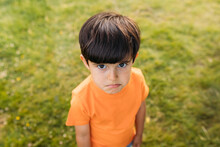 Funny Child In T Shirt On Meadow With Sad Expression