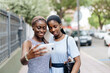 © Javier Pardina/Stocksy - Two female black friends with mobile phone