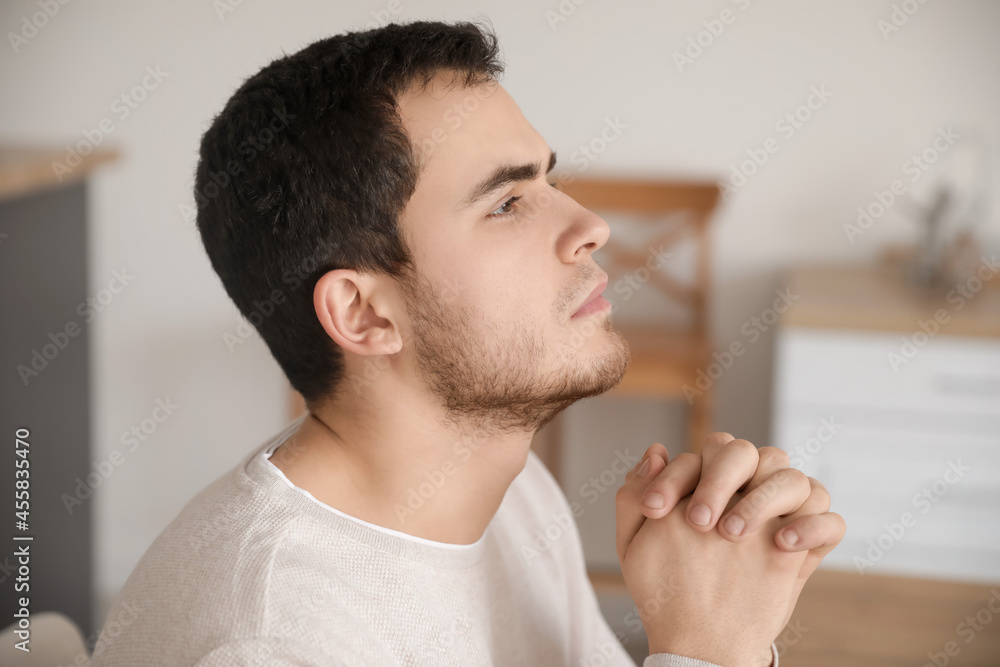 Praying young man at home
