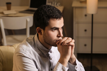 Wall Mural - Young man praying at home in evening