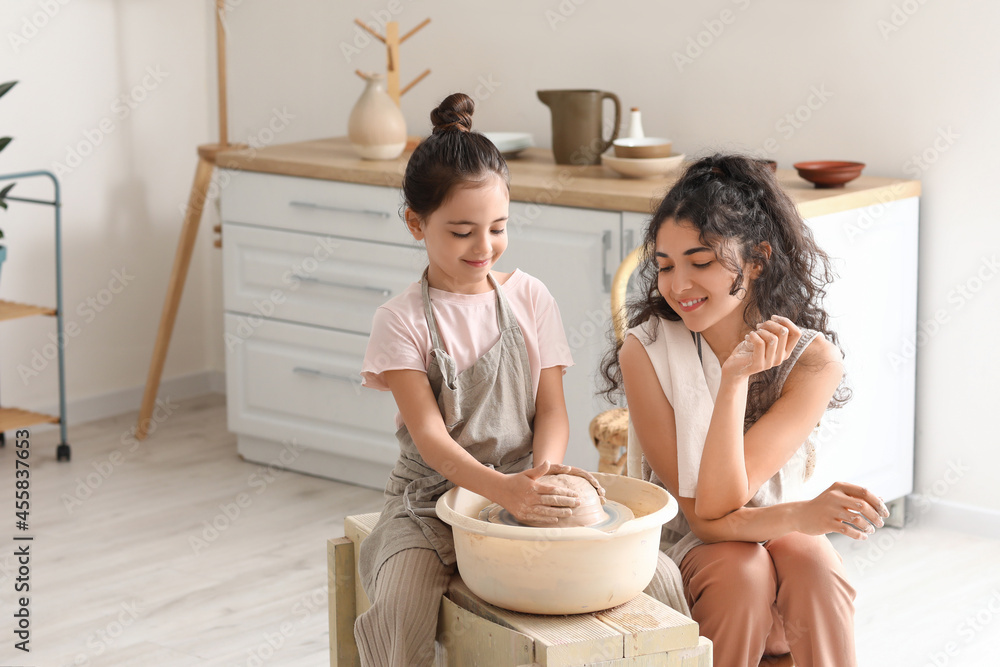 Little girl with her mother making ceramic pot at home