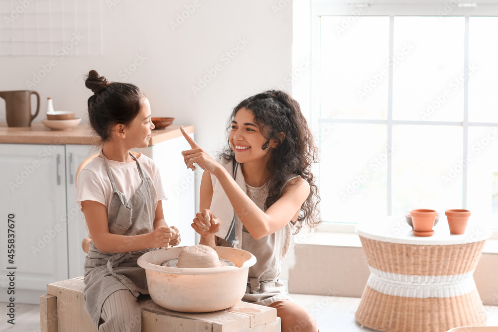 Little girl with her mother making ceramic pot at home