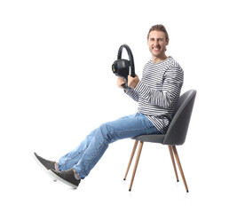 Young man with steering wheel sitting on chair against white background