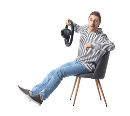 Young man with steering wheel sitting on chair against white background