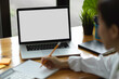 © bongkarn - Closeup young female college student sitting at table doing assignment, laptop screen mockup