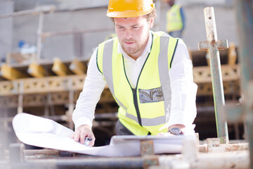 Portrait confident engineer with blueprints at construction site