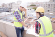 © KOTO - Construction worker engineer reviewing blueprints at highrise construction site