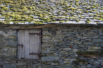 Wall Mural - Old stone house with green moss on the roof