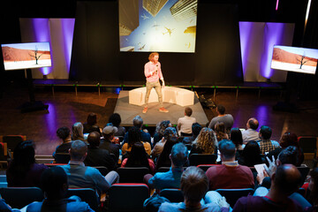 Audience watching male speaker on stage