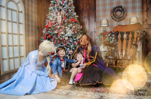 Kids With The Main Characters Of Disney Elsa And Anna Cold Heart Waiting For Santa Claus For The New Year And Christmas At Home Against The Background Of The Tree