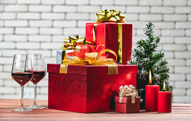 Festive red gift box and red lighten candles on natural wood board decorate with Christmas tree, Backgound of blurred white brick wall background.