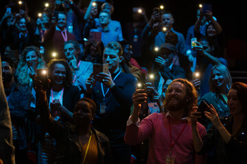 Wall Mural - Smiling audience using smart phone flashlights for speaker