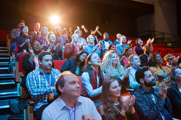 Happy audience clapping in dark room