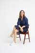 © Martin Villadsen - Happy and beautiful young woman sitting on chair with her legs crossed and with white shoes and denim clothing while smiling and looking in camera