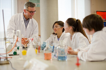 Wall Mural - male teacher and students conducting scientific experiment in laboratory classroom
