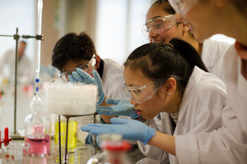 Wall Mural - female teacher and students watching scientific experiment chemical reaction in laboratory classroom