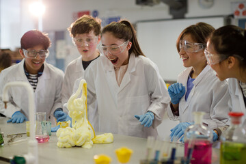 Wall Mural - surprised students conducting exploding foam scientific experiment in classroom laboratory