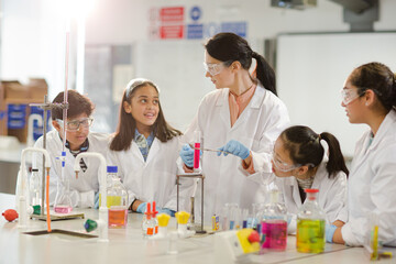 Wall Mural - female teacher and students conducting scientific experiment, watching liquid in test tube in labora