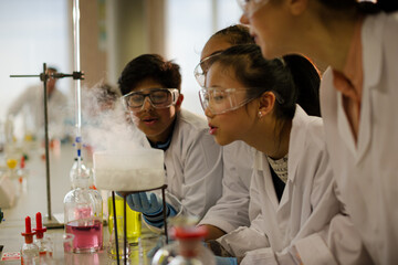 Wall Mural - female teacher and students watching scientific experiment chemical reaction in laboratory classroom
