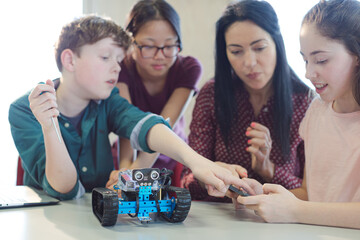 Wall Mural - female teacher and students playing with robot in classroom