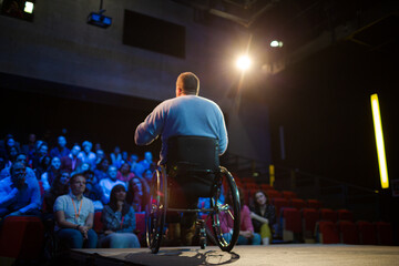 Audience watching male speaker in wheelchair talking on stage