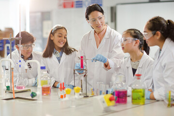 Wall Mural - female teacher and students conducting scientific experiment, watching liquid in test tube in labora