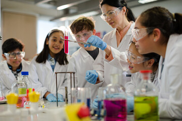 Wall Mural - female teacher and students conducting scientific experiment, watching liquid in test tube in labora