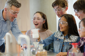 male teacher and students watching chemical reaction, conducting scientific experiment in laboratory