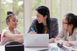 © KOTO - Female teacher and girl students using laptop at table