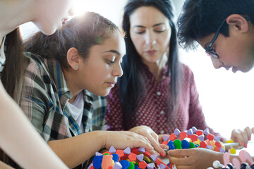 Wall Mural - female teacher and students examining dna model in classroom