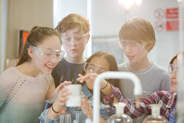 Wall Mural - curious, smiling students watching chemical reaction, conducting scientific experiment in laboratory