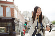 © KOTO - Smiling young woman commuting on bicycle, talking on cell phone on sunny urban street