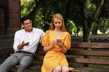 Poster - Young woman with smartphone ignoring her boyfriend in park. Boring date