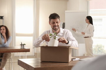 Poster - New coworker unpacking box with personal items at workplace in office