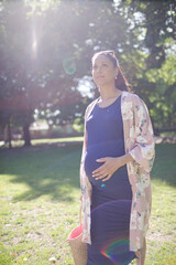 Wall Mural - Pregnant woman walking in sunny park