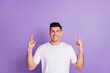 © deagreez - Photo of young guy happy positive smile look indicate fingers empty space suggest promo advert isolated over purple color background